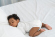 © ronnachaipark - black african american baby sleeping on a white mattress.