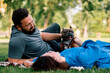 a married couple rests in nature lies on a sheet in the park plays with a small dog of the French bulldog breed