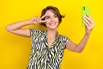 Sticker - Photo of adorable pretty girl dressed zebra print shirt show v-sign near eye make selfie on smartphone isolated on yellow color background