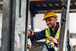 © kanpisut - Man worker at forklift driver happy working in industry factory logistic ship. Man forklift driver in warehouse area. Forklift driver sitting in vehicle in warehouse