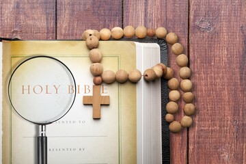 Holy Bible with cross and magnifying glass