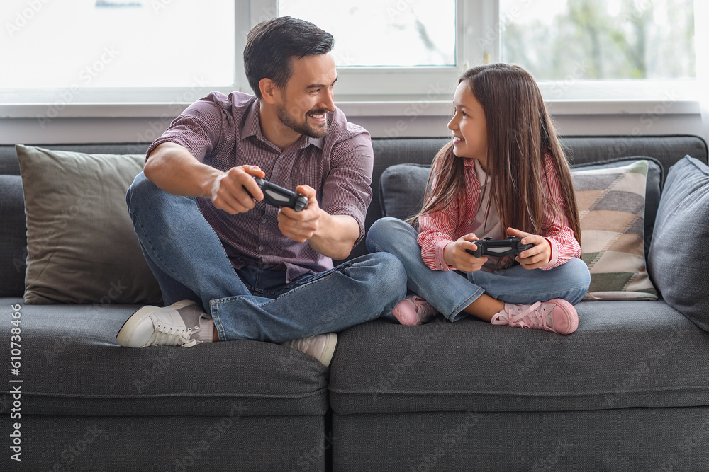 Father with his little daughter playing video game at home