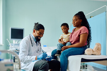 Wall Mural - Black mother and son talk to pediatrician at medical clinic.