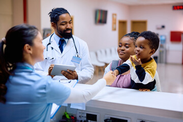 Wall Mural - Happy black kid handshaking with reception nurse at pediatric clinic.