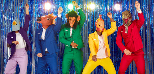 People in different silly animal masks having fun at crazy party. Group of people in colorful suits and funny bird, horse, ape, chicken and dino masks dancing gangnam style on foil fringe background