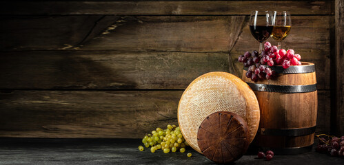 Wall Mural - Glass of red wine, cheeses and grapes on a wooden background, A head of hard cheese, Long banner format