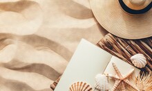 A Book, Hat, And Sea Shells On A Beach Towel With A Straw Hat On Top Of The Book And A Starfish On The Beach.  Generative Ai