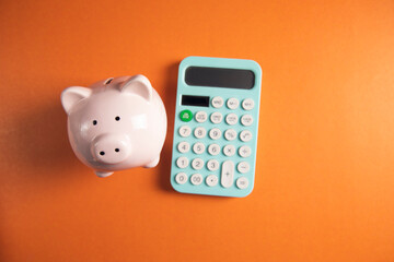 Poster - piggy bank with calculator in orange background