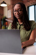 © DC Studio - Focused african american entrepreneur working from home typing and looking at laptop screen in home living room. Portrait of freelancer doing remote work on portable computer at desk.