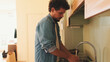 © Andrii Nekrasov - Guy dressed in denim shirt washes vegetables in the kitchen in the apartment