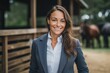 Portrait of a smiling businesswoman in a suit standing in a horse stable