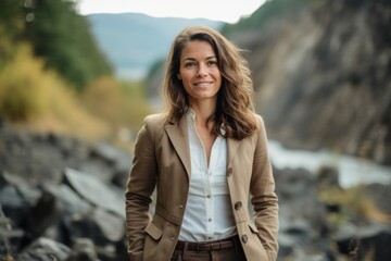 Wall Mural - Portrait of a beautiful woman in a beige jacket on the background of a mountain river