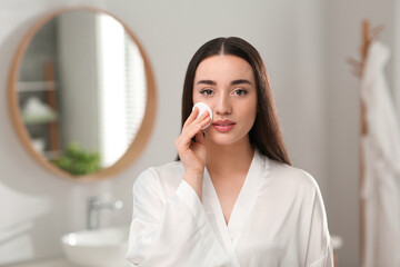 Wall Mural - Beautiful woman removing makeup with cotton pad indoors