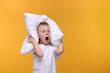 Sleepy boy with pillow yawning on orange background, space for text. Insomnia problem
