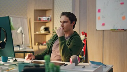 Wall Mural - Focused artist staring computer display in evening office. Serious man working