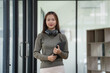 © Songsak C - Smiling young Asian businesswoman holding a digital tablet standing in an office.