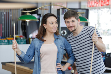 young couple playing snooker together in bar