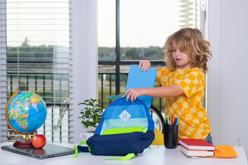 Fototapete - School kid student puts school supplies in a backpack. Preparation for school. Elementary school child doing homework in room. Nerd pupil studying at home.