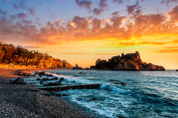 scenic sea shore view of island in ocean with waves and amazing cloudy sunset or sunrise on backgeound