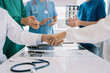 © NINENII - Doctors holding hands together at hospital.