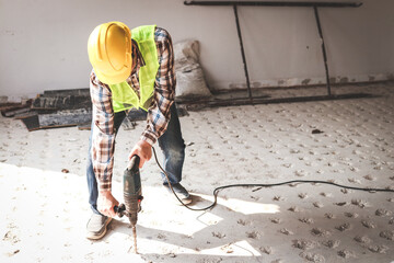 Asian construction worker using mortar extraction machine to drill concrete floor. Industry concept, construction technology