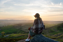 Woman In Green Dress Reaching The Destination, Sitting And Resting  On Top Of Mountain In The Peak District  At Sunrise.   Local Tourism Concept.