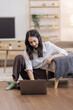 © David - Portrait of a young happy asian female freelancer sitting on the couch and working on project, watching movie on laptop, studying, blogging, resting and chatting online.