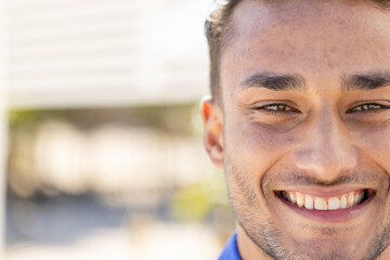 Wall Mural - Close-up portrait of handsome caucasian young man with brown eyes smiling and looking at camera