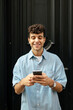 © Imanol - Young man with curly hair using smartphone