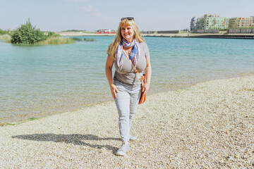 Portrait attractive middle-aged woman of plump forms on shore sea or lake