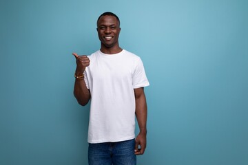 handsome 30s african man with short haircut in white t-shirt shows his hand towards space