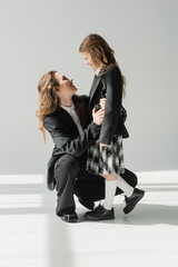 Wall Mural - modern mother and daughter, businesswoman in suit hugging schoolgirl in uniform with plaid skirt, blazers, getting ready for new school year, encouraging, looking at each other