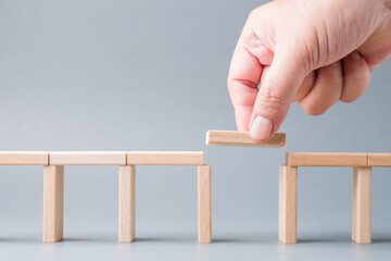 Closeup hand fill a final piece of wood between the gap of a toy bridge, solution to solve the disconnect problem