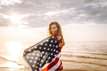 Young woman with  American flag on the beach. Patriotic holiday. USA celebrate 4th of July. Independence Day concept