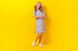 © deagreez - Full length photo of shiny thoughtful woman dressed flower print sarafan arms crossed looking empty space isolated yellow color background