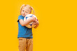 © somemeans - Little blonde girl holding soccer ball on yellow studio background. Copy space, mockup. Football for kids concept.