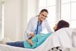 © Studio Romantic - Friendly gynecologist doctor examining heartbeat in the abdomen of pregnant young woman lying on the couch in medical clinic. Obstetrician doctor checking her patient expecting a baby.