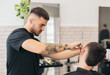 © ADDICTIVE STOCK - Young barber cutting beard with razor blade in hair salon