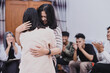 © Queenmoonlite Studio - Young women embracing each other in support group meeting or therapy session while others clapping their hands showing support. Concept of psychological help and therapy counseling