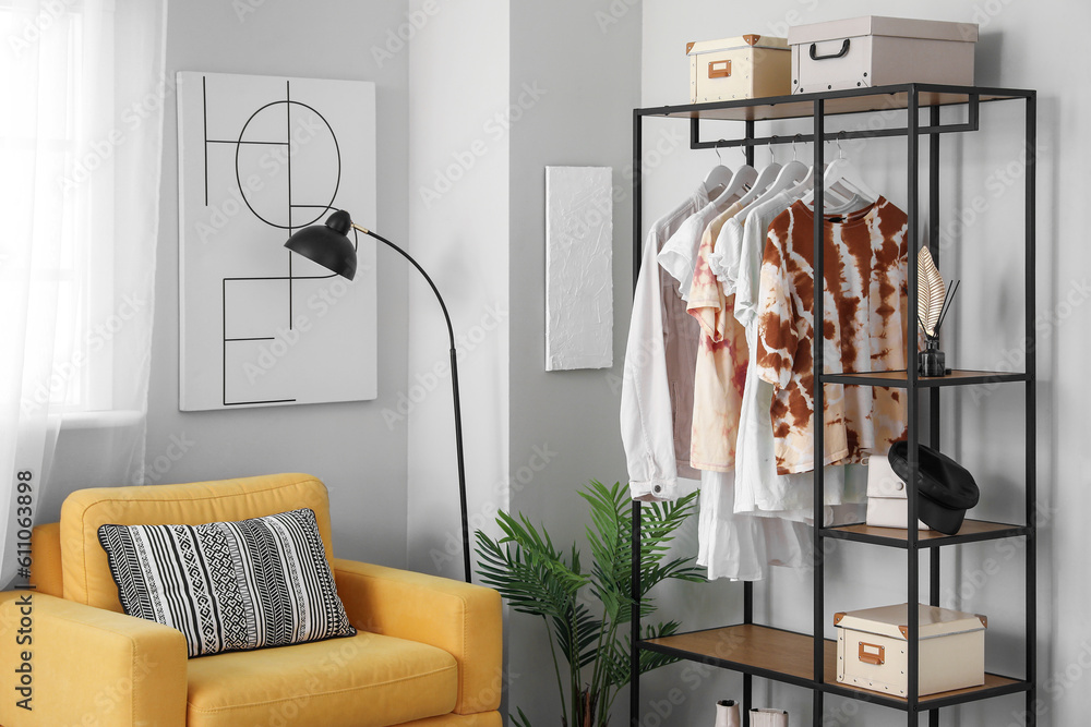 Shelving unit with clothes and accessories in interior of light room