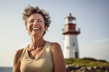 Wall Mural - Close-up portrait photography of a happy mature girl practicing yoga against a lighthouse background. With generative AI technology