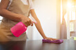 Cleaning staff is wiping cloth with cleaner and disinfectant on the surface of table to make the table clean with cleaning products and free from germs clinging to surface of the table in living room.