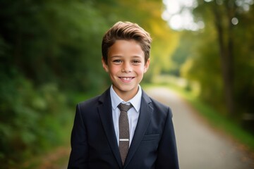 Sticker - Close-up portrait photography of a grinning kid male wearing a sleek suit against a serene nature trail background. With generative AI technology