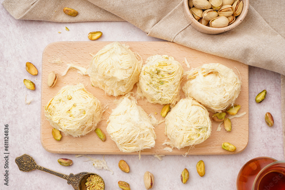 Wooden board with tasty Turkish Pismaniye on light background
