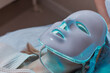LED light anti-aging mask for facial skin care in a spa slow motion. A woman lies on a couch in a special mask. Modern technologies of beauty and health.
