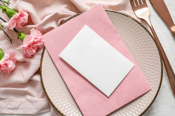 clean plate with blank invitation card and carnation flowers, closeup