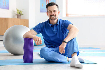 Sticker - Male physiotherapist with foam roller in rehabilitation center