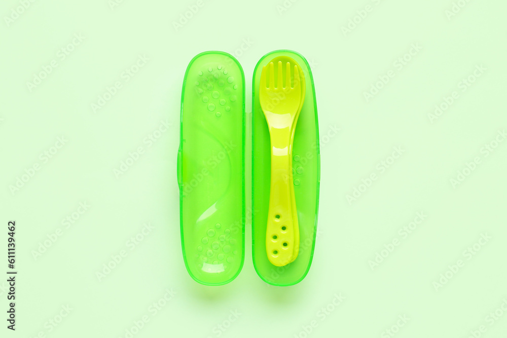 Yellow eating utensils for baby on pale green background