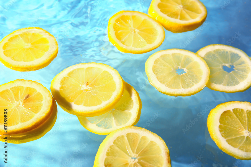 Slices of fresh lemon in water on blue background