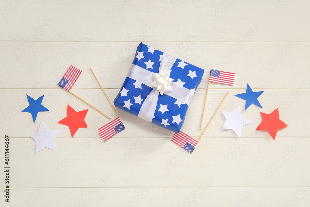 Gift box with USA flags and stars on white wooden background. American Independence Day